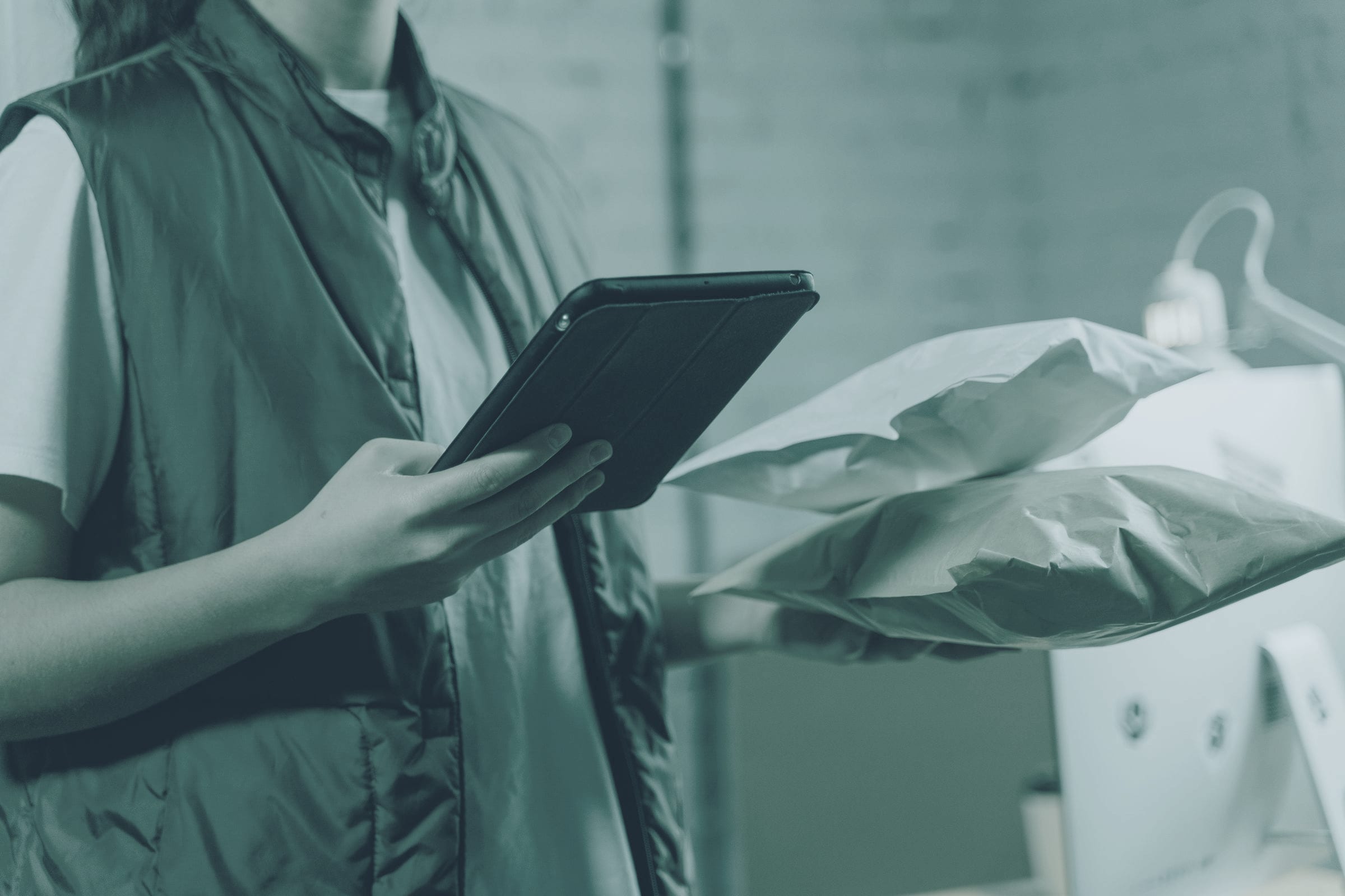 Hands holding a tablet among parcels, with no face shown.