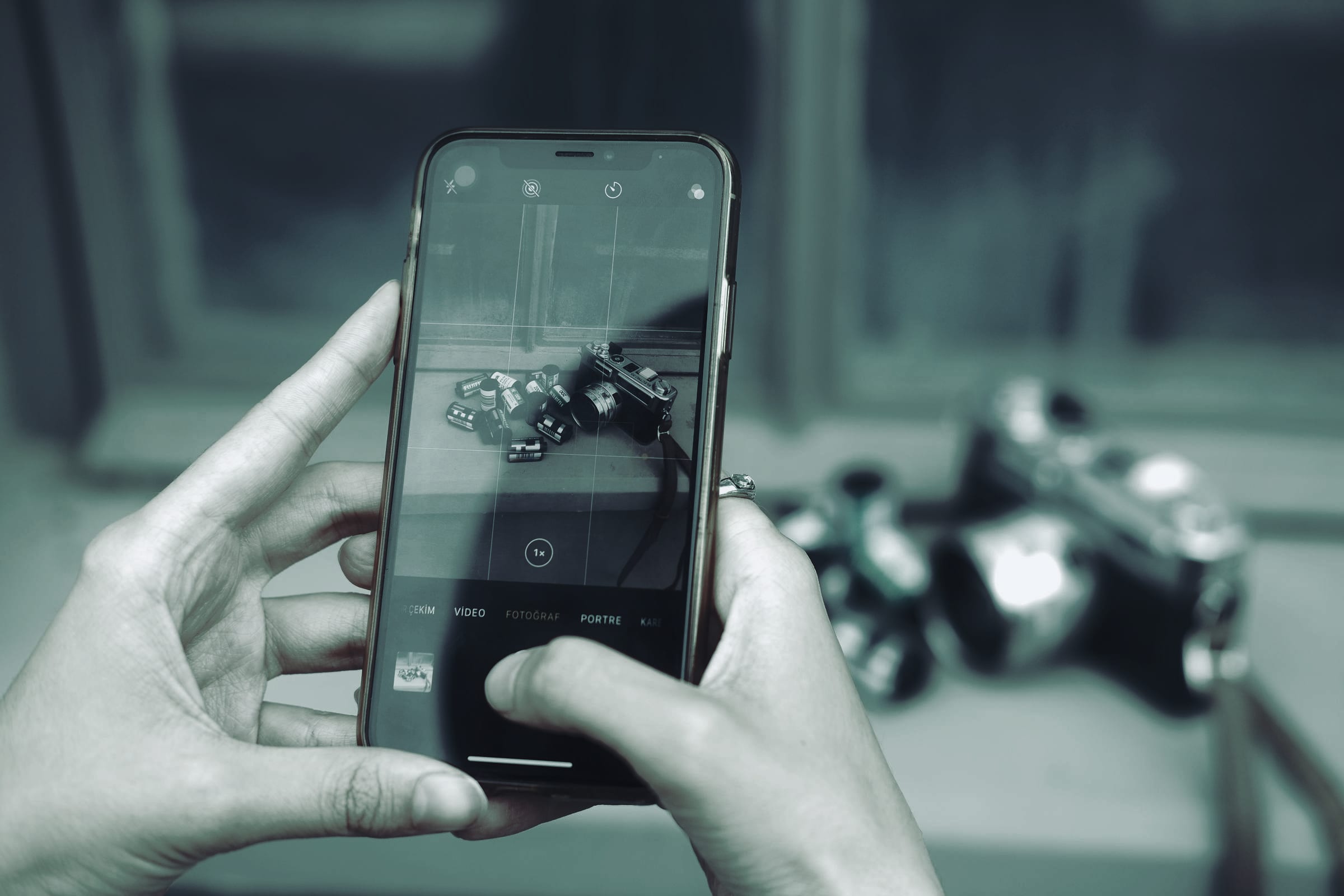 Hands photographing a camera with a phone.